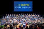 About 100 UC Davis medical students in blue caps and gowns sit on stage at the Center during their 2018 commencement