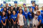 Students wearing blue SHINES shirts stand side-by-side with professors in classroom