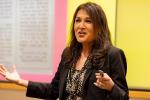 California Surgeon General Diana Ramos wearing dark blazer gestures with both hands near podium in UC Davis lecture hal