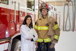 Firefighter standing next to a female doctor in a firehouse next to a fire engine