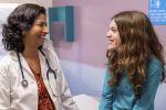 Female doctor with teen girl in patient room