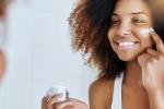 Woman rubbing lotion on her face
