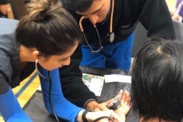 Photo of Vanessa Mora and a UC PRIME colleague taking a patient's blood pressure at a San Joaquin Valley health clinic.