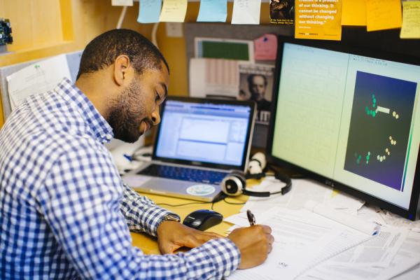 UC researcher sitting at desk in front of a computer