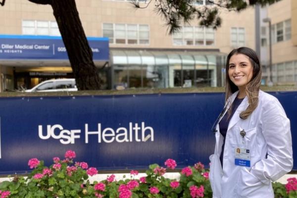 image of Vanessa Mora Molina in a white coat in front of a UCSF Health sign