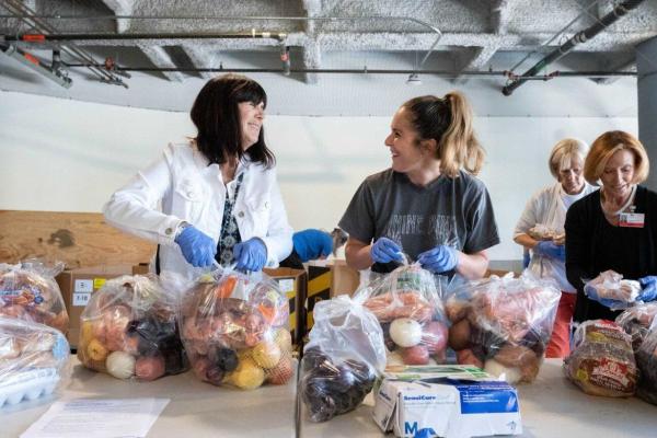 image of two people wearing clothes and sorting food at a food bank