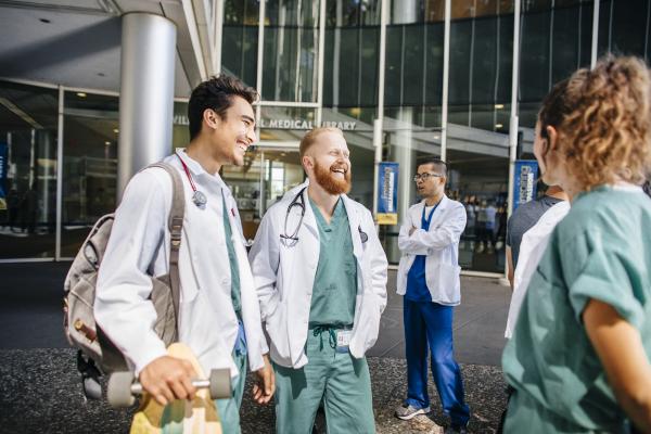 UC medical school students standing and talking in a group in front of a hospital