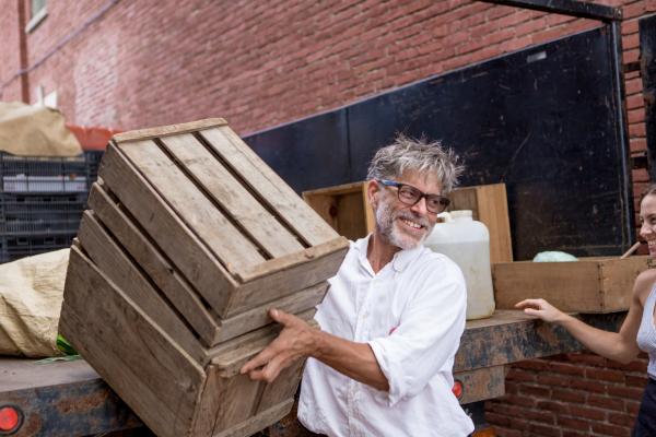 Farmer unloading crates of produce from a truck for delivery