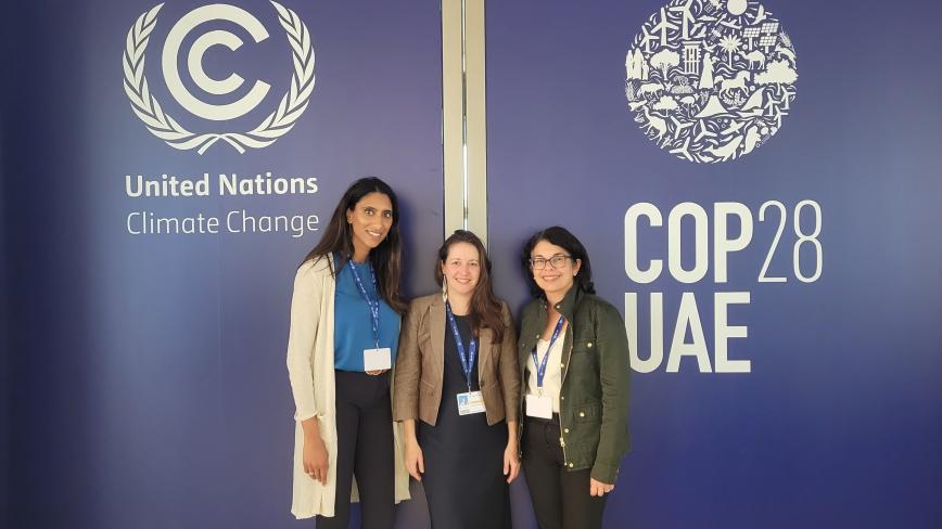 Sapna Thottathil, Jennifer Monroe Zakaras, Arianne Teherani from the UC Center for Climate, Health and Equity in front of a COP28 official sign in Dubai