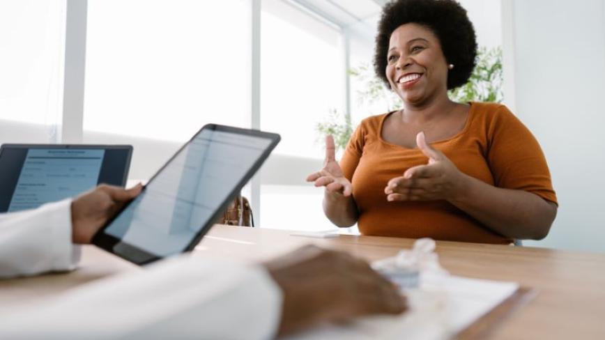 patient speaking to a health care provider who is holding a tablet