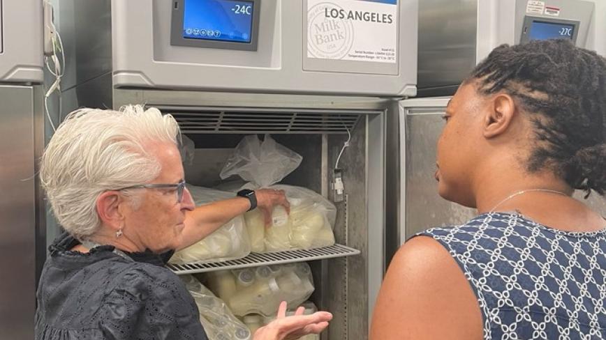 two people looking in a fridge holding donor milk