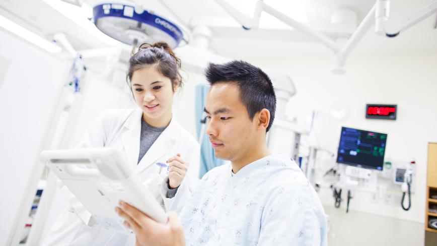 clinician in a white coat looking at a chart with a patient 