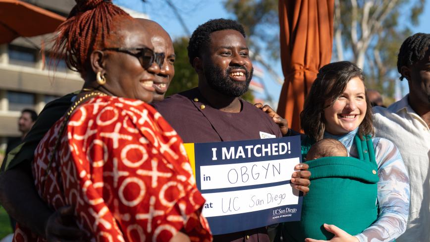 photo of a student holding an "I matched" sign with his family