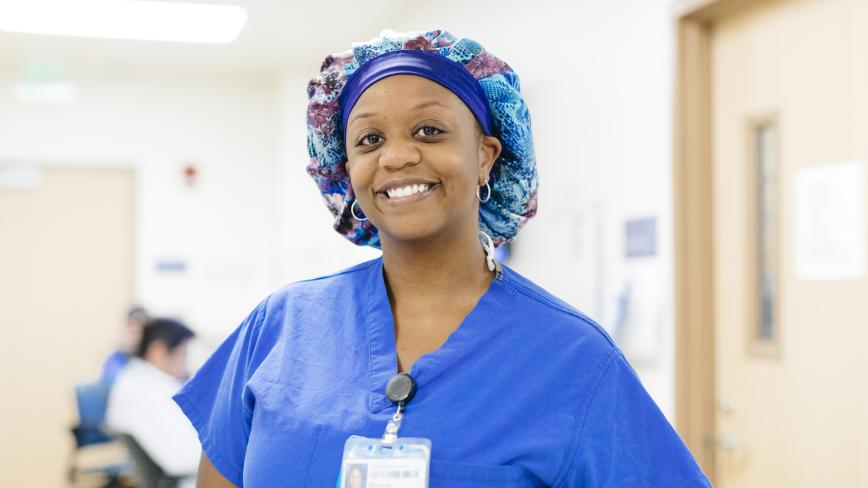 nurse standing in a hallway wearing blue scrubs
