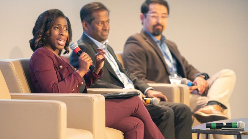 Image of a woman speaking on a panel with two other people