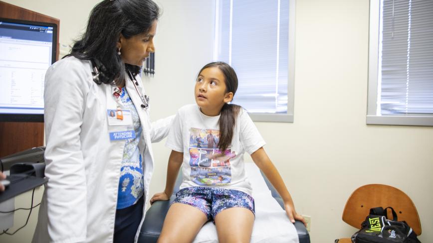 image of a physician in a white coat in a doctor's office speaking to a child