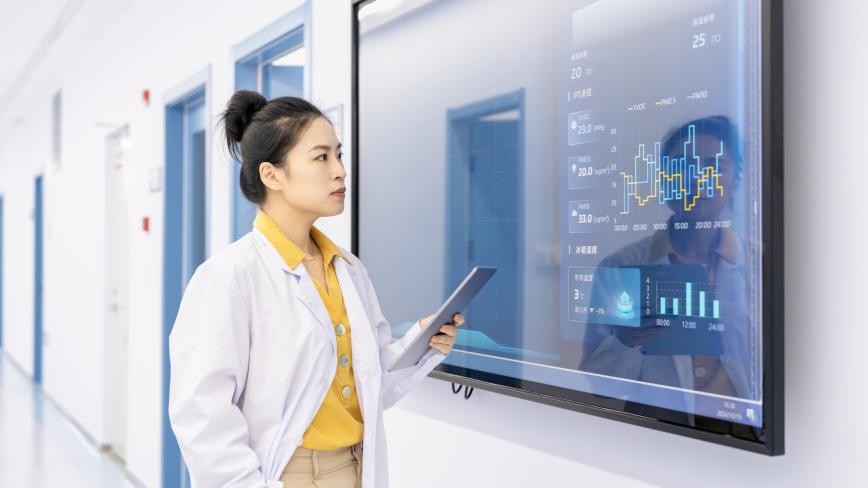 Image of a healthcare provider in a white coat looking at a screen with diagrams
